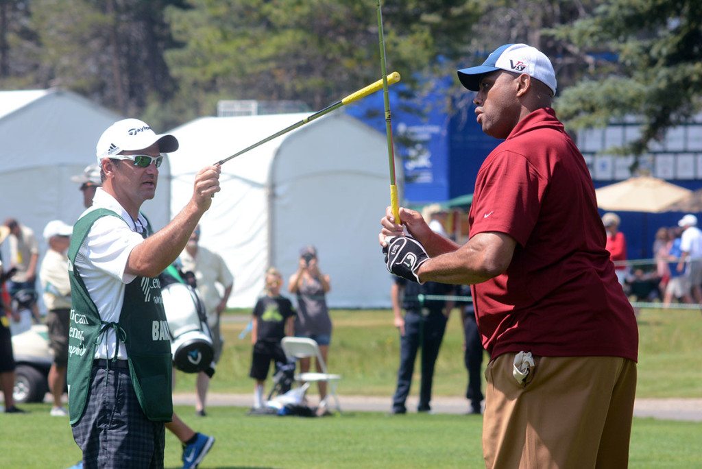 The caddy for Charles Barkley give his a pointer before the former NBA star shoots from the 10th fairway.