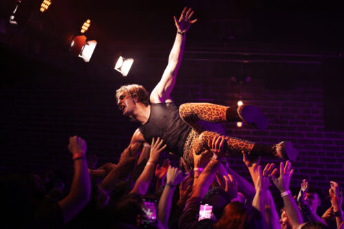 Reno's Pussy Velour vocalist, Wolfgang Hendrix, signs from atop the crowd during their live concert performance.